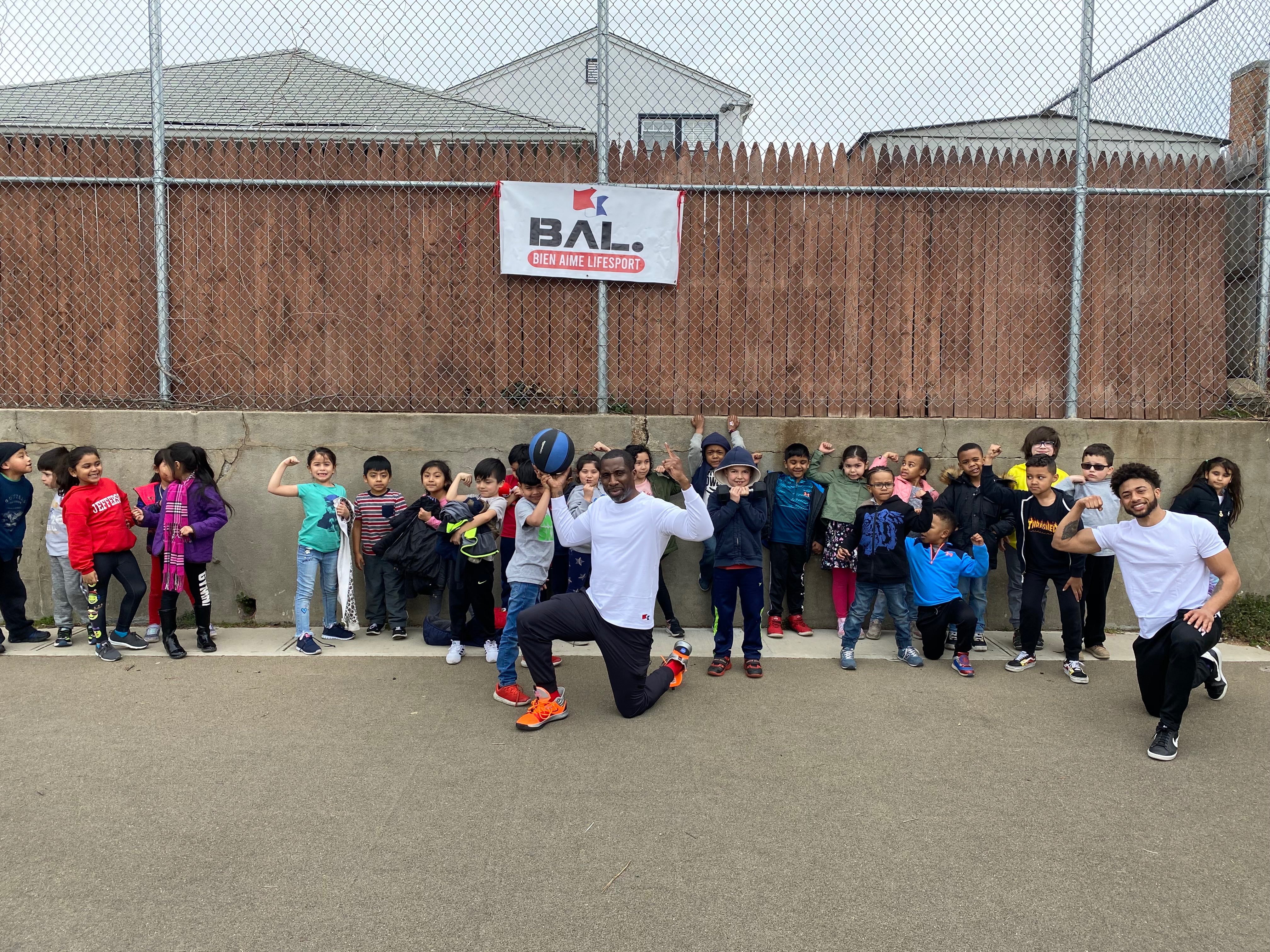 Coach Pat demonstrating fitness with large group of elementary students outdoors